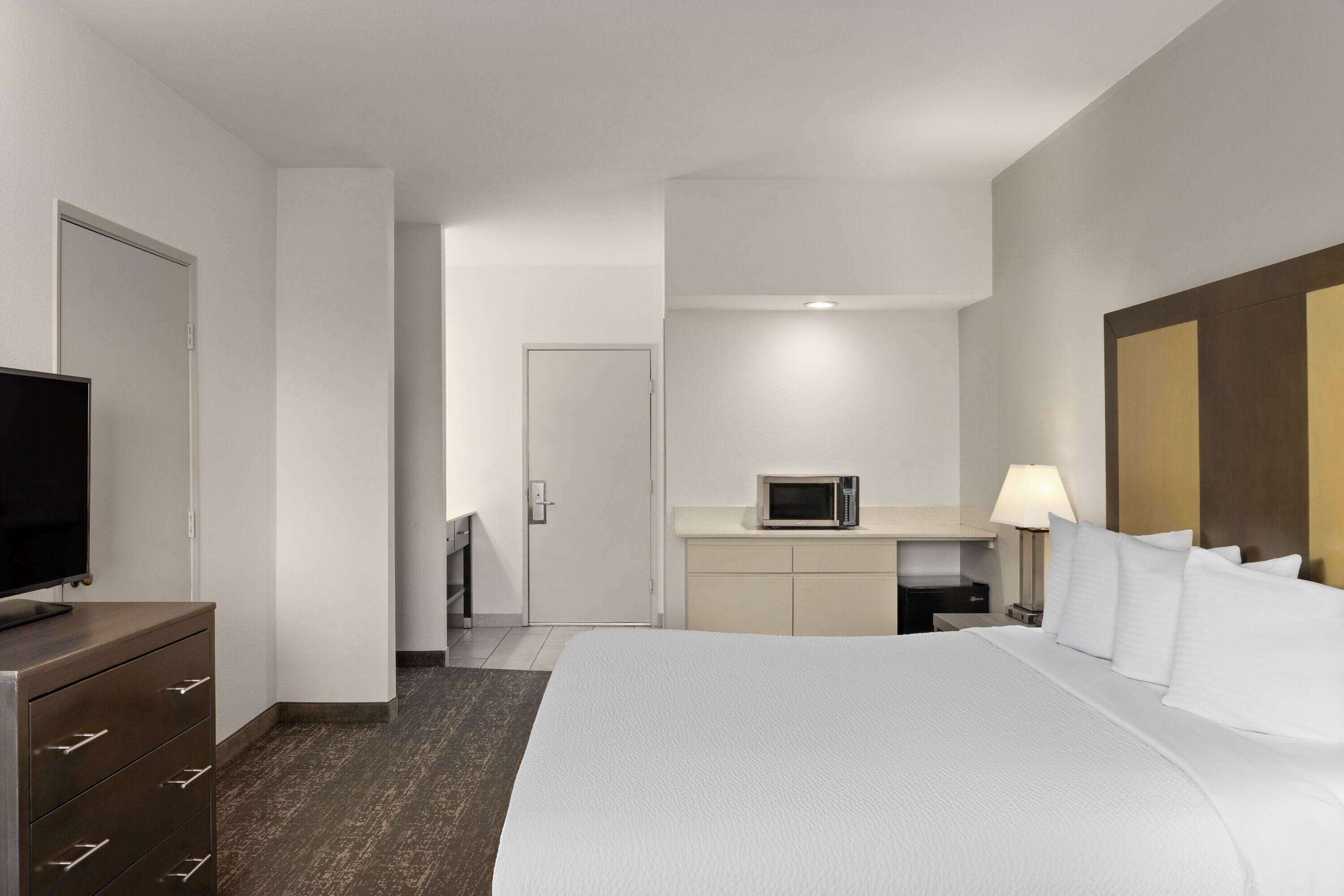 Une chambre d’hôtel équipée d’un lit, d’une télévision, d’un four à micro-ondes et d’un bureau avec une lampe.