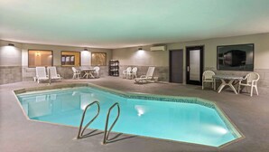 Una piscina con sillas de descanso y mesas, rodeada de muros y puertas.