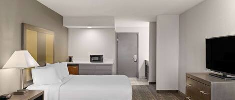 A hotel room with two beds, a desk with a microwave, a TV, and a dresser.
