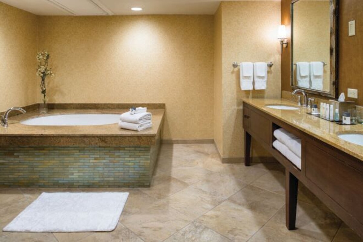 Ein Badezimmer mit einer großen Badewanne, zwei Waschbecken und einem Spiegel.