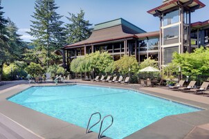Una piscina al aire libre, sombrillas, sillones reclinables de piscina