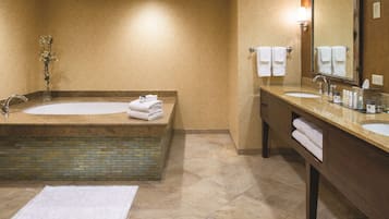 Un baño con una bañera grande, dos lavamanos, un espejo y un perchero para toallas.