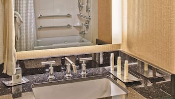 Un baño con un lavamanos, tres llaves y un espejo.