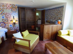 A room with a wooden bed, a wooden sofa, a small table, and a colorful patterned wall.