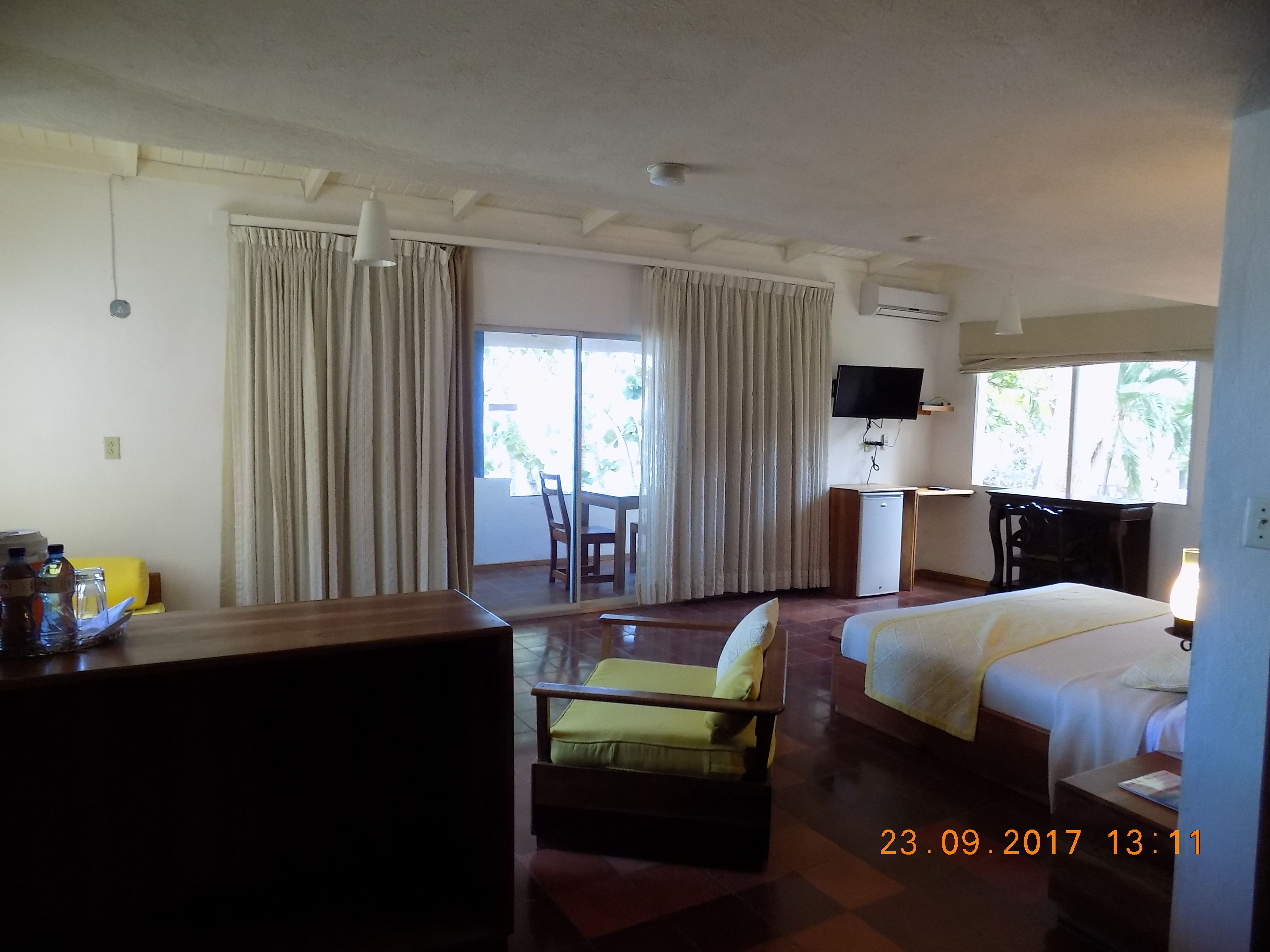 Une chambre d’hôtel équipée d’un lit, d’un bureau, d’une chaise, d’une télévision et d’une fenêtre avec des rideaux.