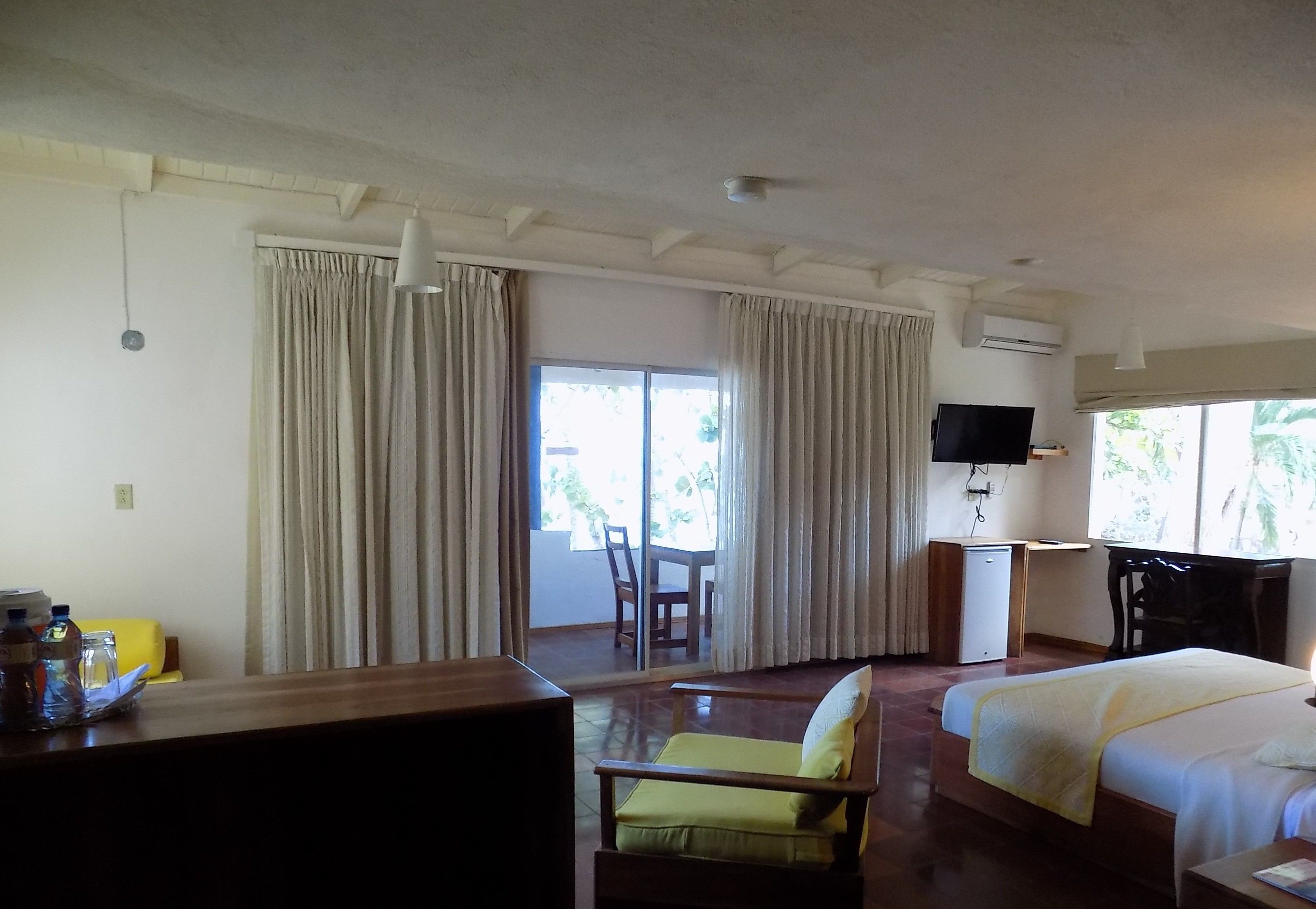 A hotel room with a bed, a desk with a chair, a television, and a view of the outdoors.
