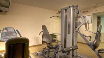 A gym with exercise equipment, a television, and a small table.