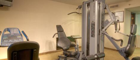 A gym with exercise equipment, a television, and a small table.