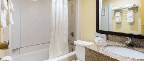 Un baño con bañera, inodoro, lavamanos y espejo.