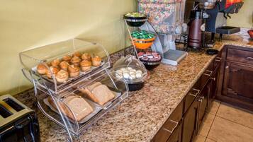 Un bufé de desayuno con muffins, huevos y pan sobre una encimera de granito.