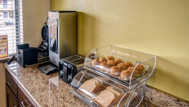 Un comptoir pour le petit-déjeuner avec un grille-pain, du pain, des muffins et une machine à café.