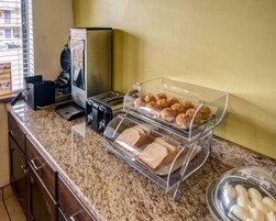 Mostrador de desayuno con tostadora, pan, muffins y una máquina de café.