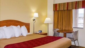 A hotel room with a bed, bedside lamps, a desk, and a chair. - Econo Lodge Albuquerque East (Albuquerque)