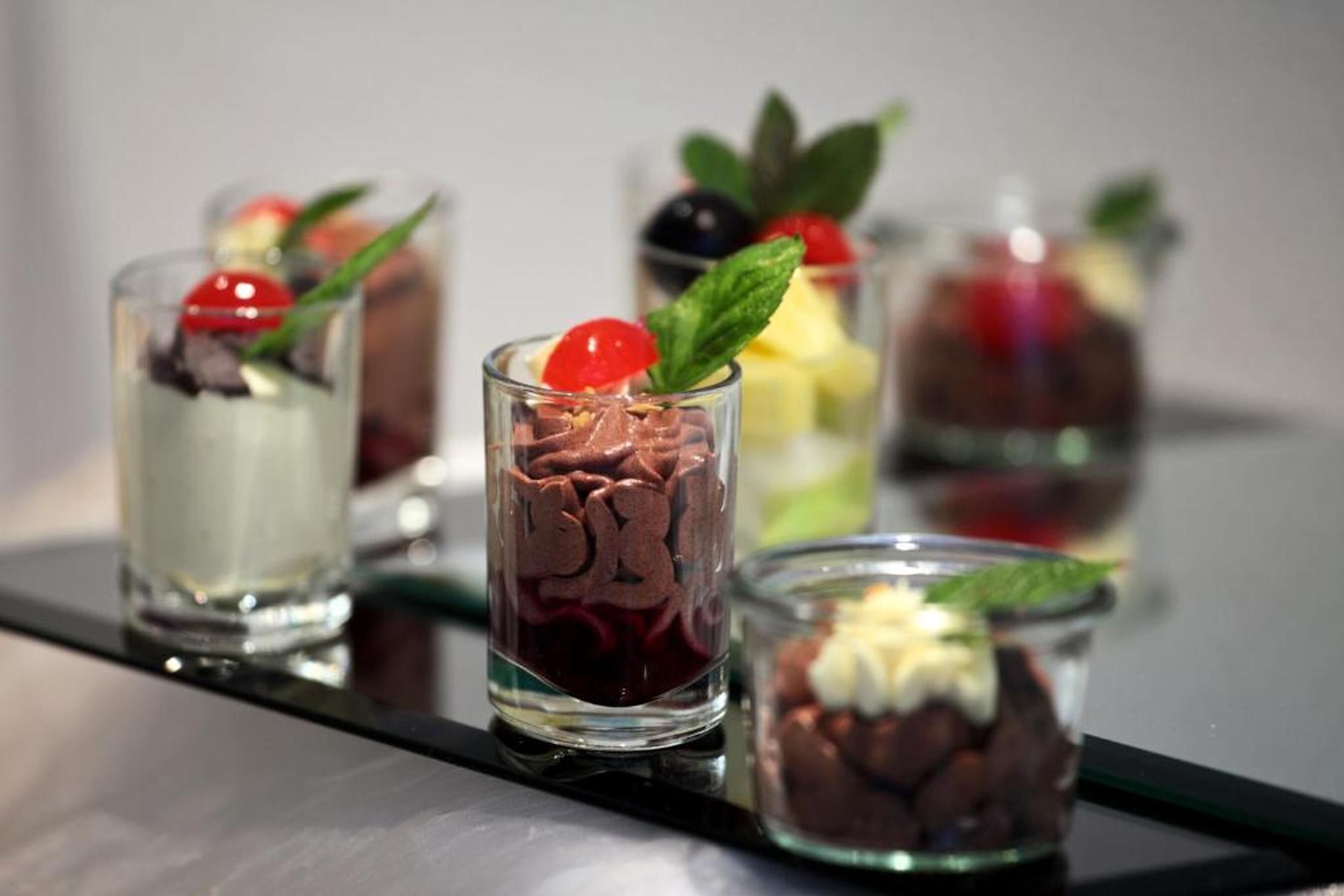 A series of dessert glasses with various toppings and garnishes.