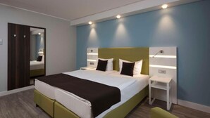 A modern hotel room with a large bed, bedside tables, a mirror, and a wardrobe. - Peine Salzgitter Hotel by Belvilla (Peine)