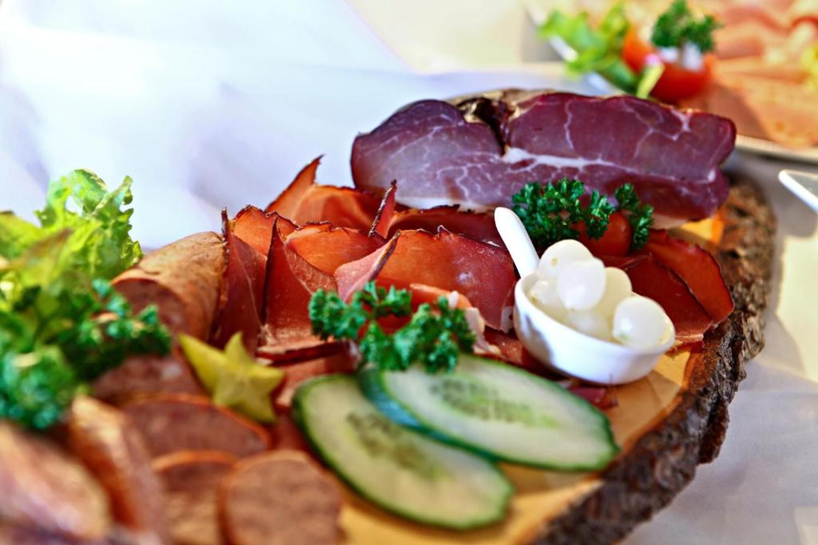 Una tabla de embutidos con diversos tipos de carne, queso y verduras.
