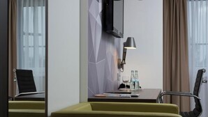 A hotel room with a desk, two chairs, a lamp, a television, and a window with curtains. - Peine Salzgitter Hotel by Belvilla (Peine)