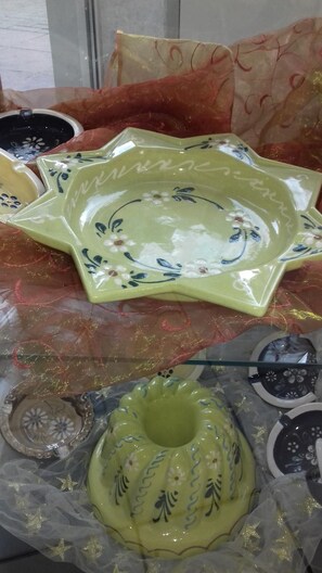 Tableware and decorative items are displayed on a table, set against a patterned backdrop.