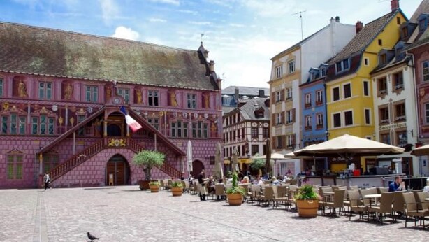 Un bâtiment historique à la façade rose, avec un escalier menant à l’entrée.