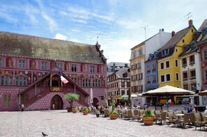 Un bâtiment historique à la façade rose, avec un escalier menant à l’entrée.