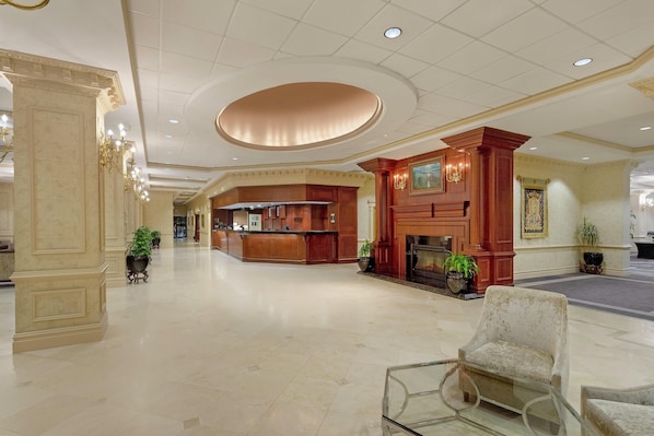 A spacious lobby with a reception desk, a fireplace, and a seating area.