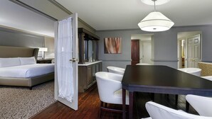 Une chambre d’hôtel comprenant un lit, une table à manger avec des chaises, un petit coin cuisine et une salle de bain.