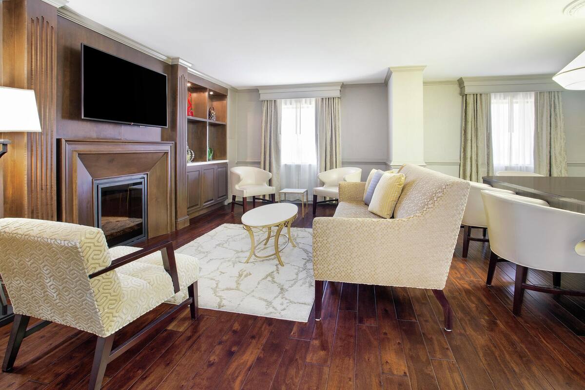 A living room with a fireplace, a flat-screen TV, and a seating area with a sofa and armchairs.