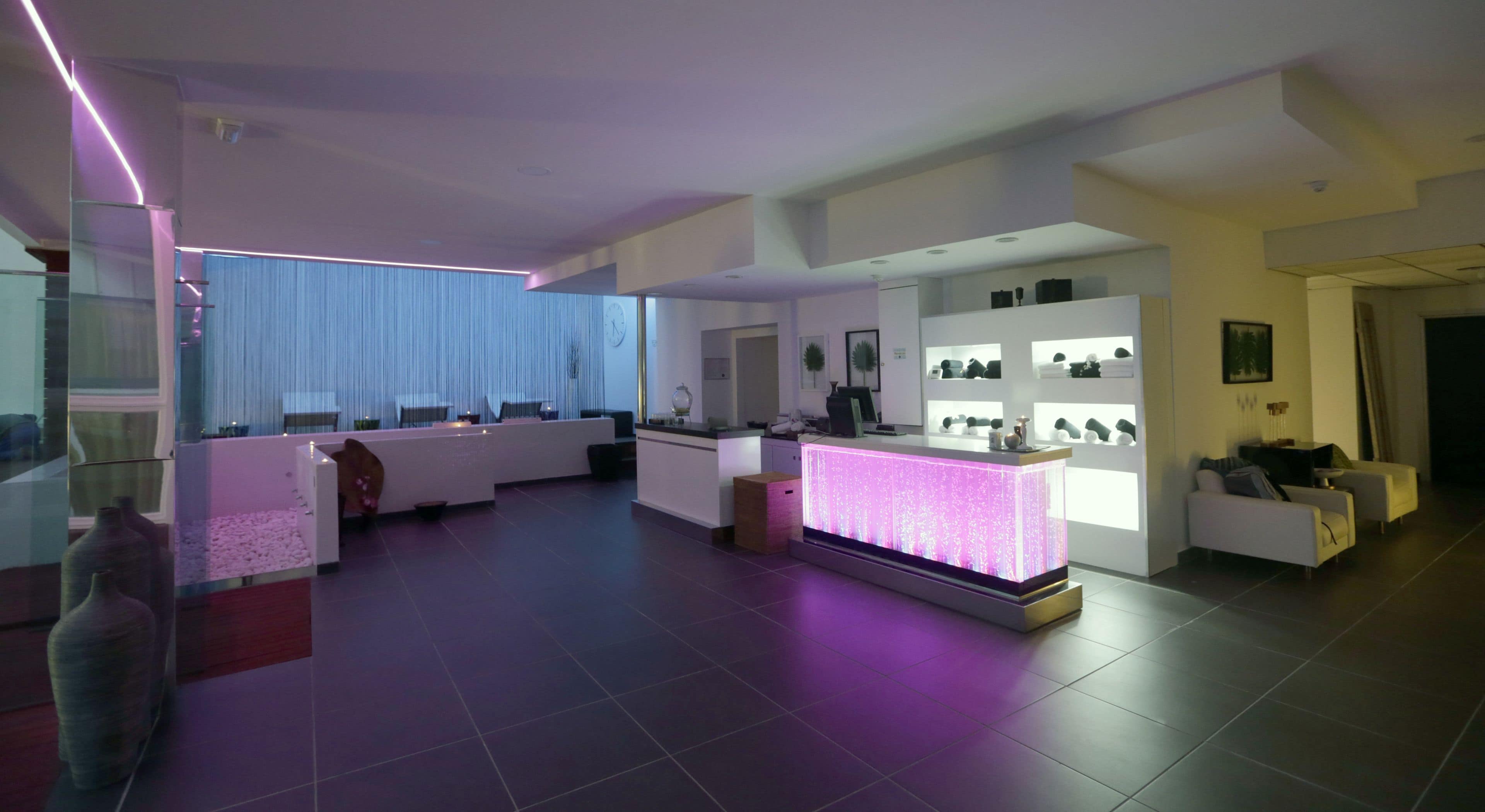 A modern living room with a reception desk, seating area, and a display of items on shelves.