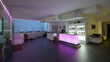 A modern living room with a reception desk, seating area, and a display of items on shelves.
