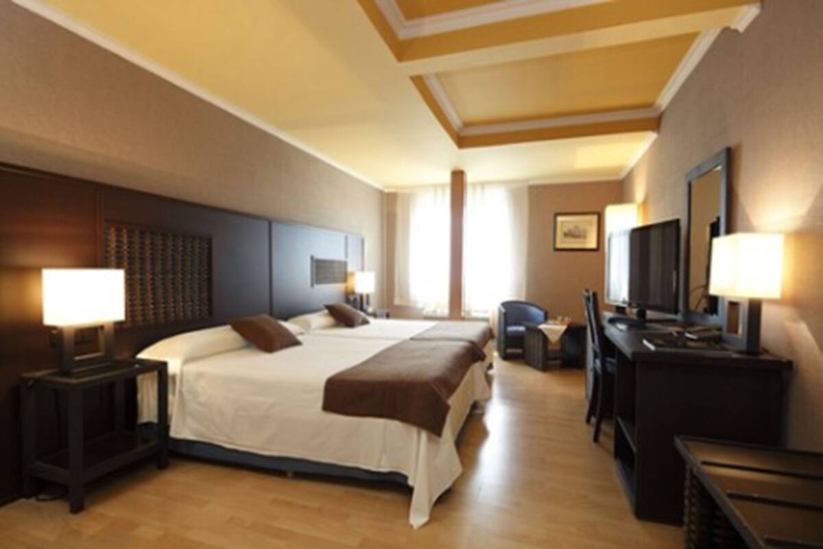 Une chambre d’hôtel avec un grand lit, un bureau, une chaise et un téléviseur.