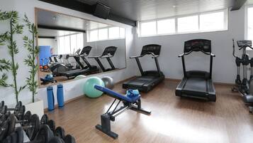 Un gimnasio con cintas de correr, pelotas de ejercicio y equipamiento de levantamiento de pesas.