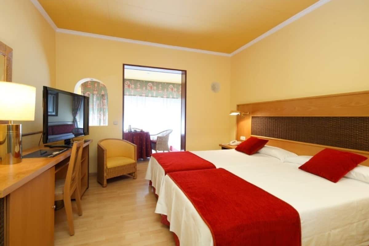 Une chambre d’hôtel comprenant un lit, un bureau avec un ordinateur, une chaise et un téléviseur.