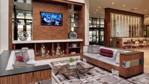A modern living room with a sofa, coffee table, and TV. - Marriott East Lansing at University Place (East Lansing)
