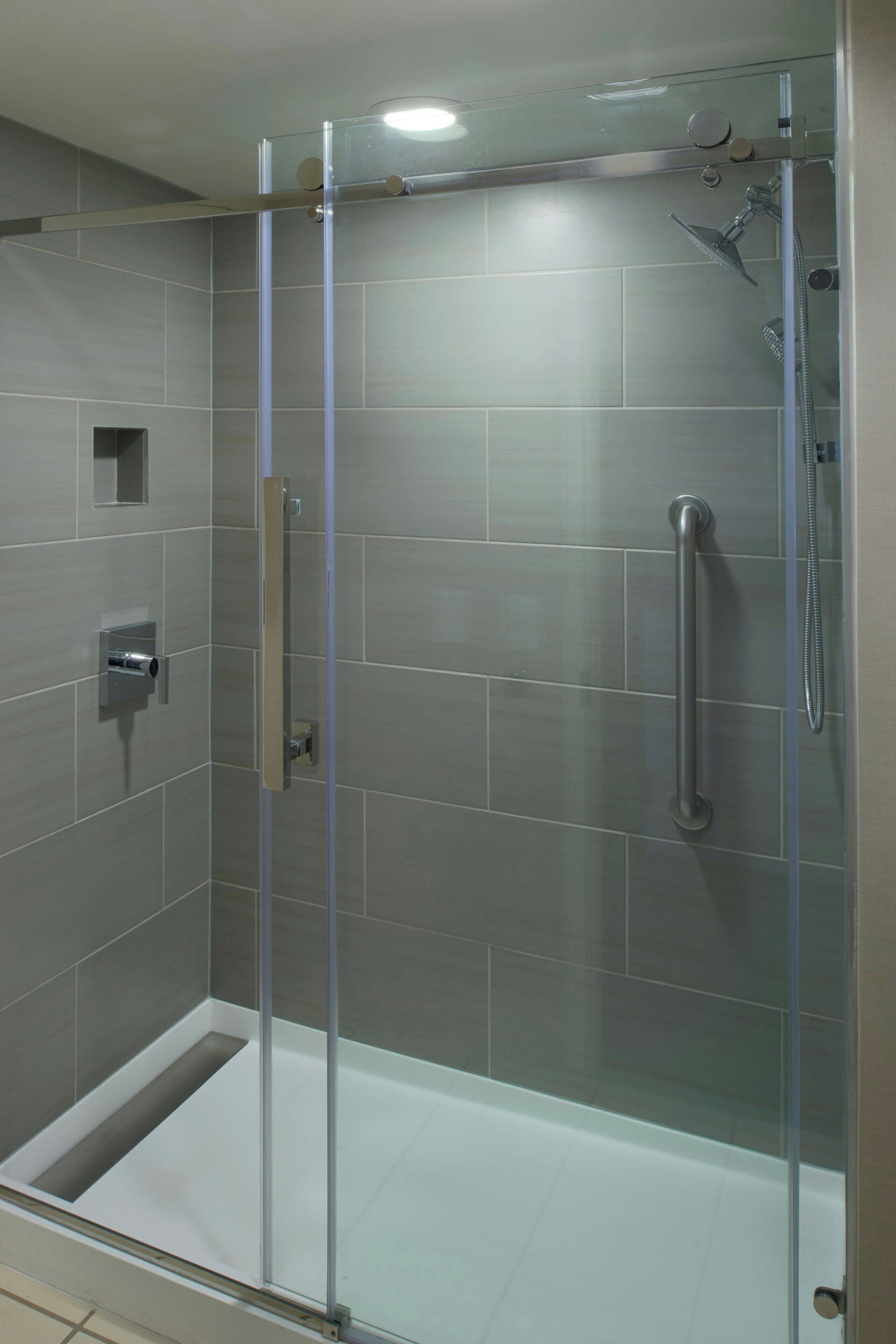 Une cabine de douche moderne dotée d’une porte en verre, d’un pommeau de douche à main et d’un système de commande de douche à main.