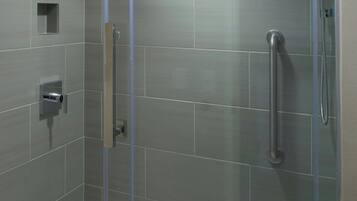 Une cabine de douche moderne dotée d’une porte en verre, d’un pommeau de douche à main et d’un système de commande de douche à main.