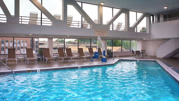 An indoor swimming pool with lounge chairs and a sign indicating no lifeguard on duty. - Marriott East Lansing at University Place (East Lansing)