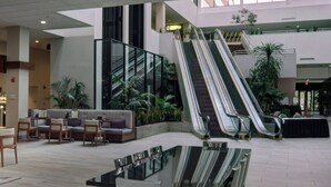 A spacious lobby with a glass coffee table, seating area, and an escalator. - Marriott East Lansing at University Place (East Lansing)