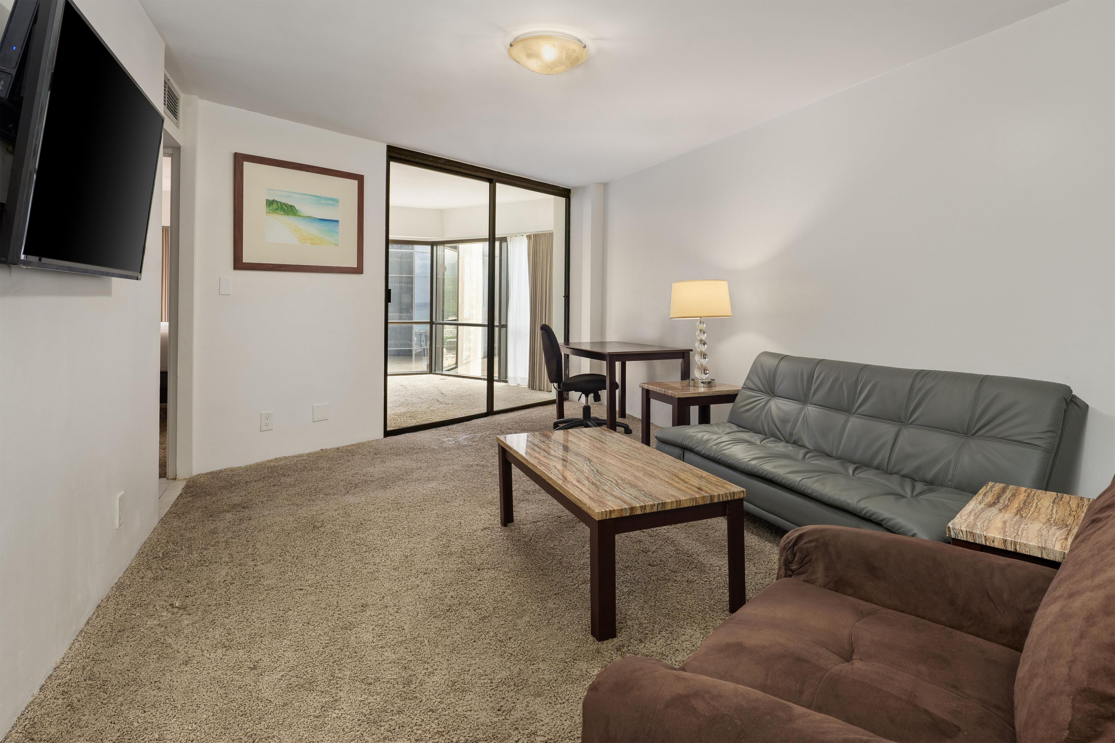 A living room with a sofa, a coffee table, a TV, and a painting.