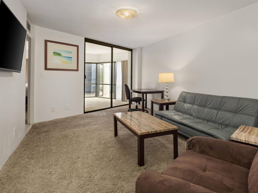 A living room with a sofa, a coffee table, a TV, and a painting.