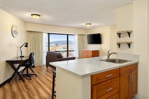 Habitación de hotel con kitchenette, un amplio ventanal con vistas, un televisor de pantalla plana y un escritorio con silla.