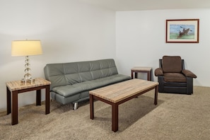 A living room with a sofa, a chair, a coffee table, a lamp, and a painting on the wall. - Aston at the Executive Centre Hotel (Honolulu)