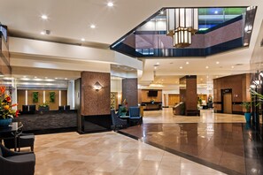 A spacious lobby with a reception desk, seating area, and a staircase leading to an upper level. - Aston at the Executive Centre Hotel (Honolulu)