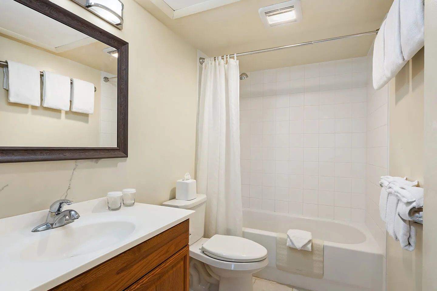 Un baño con lavamanos, espejo, inodoro y bañera.