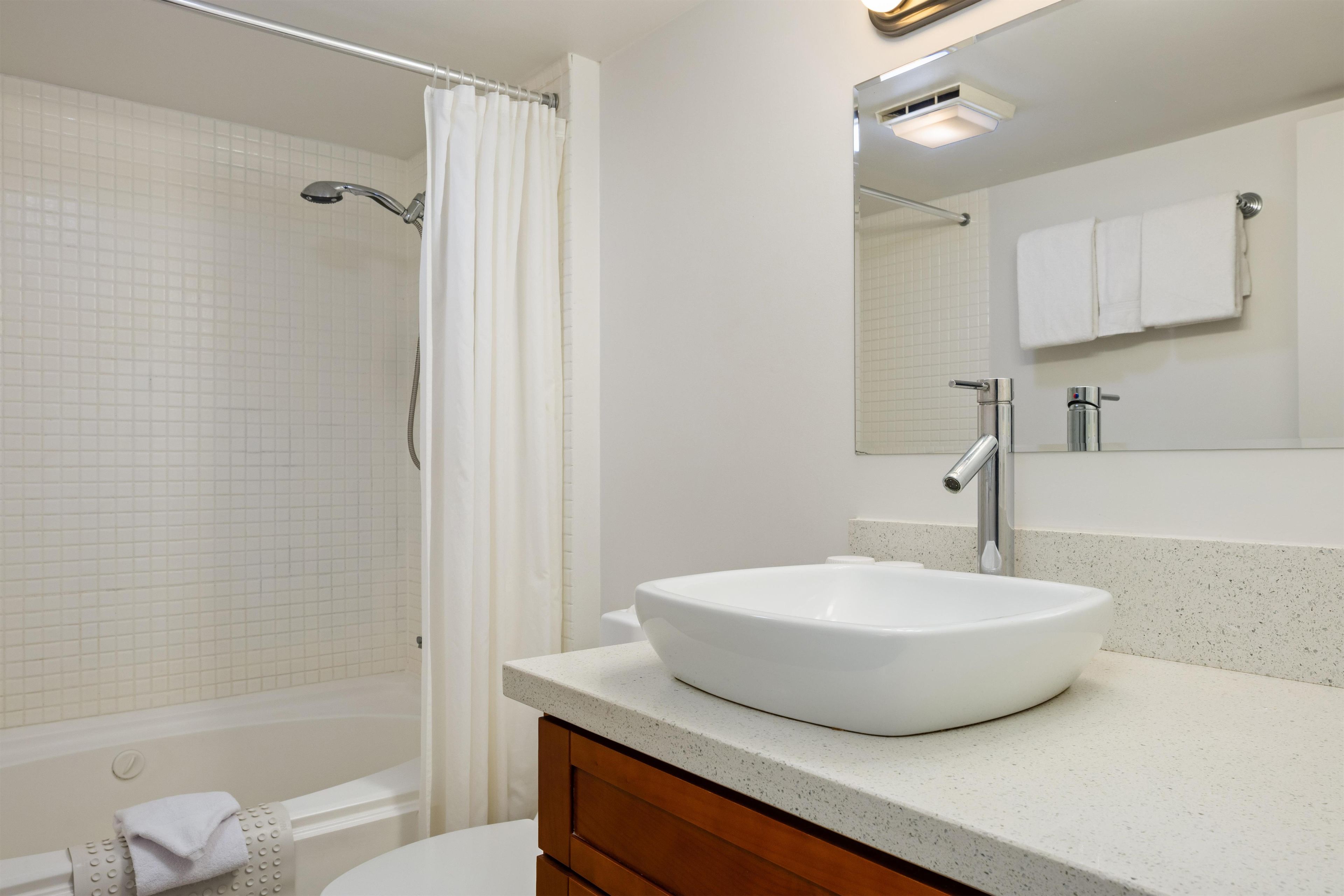 A bathroom with a white sink, a shower, and a toilet.