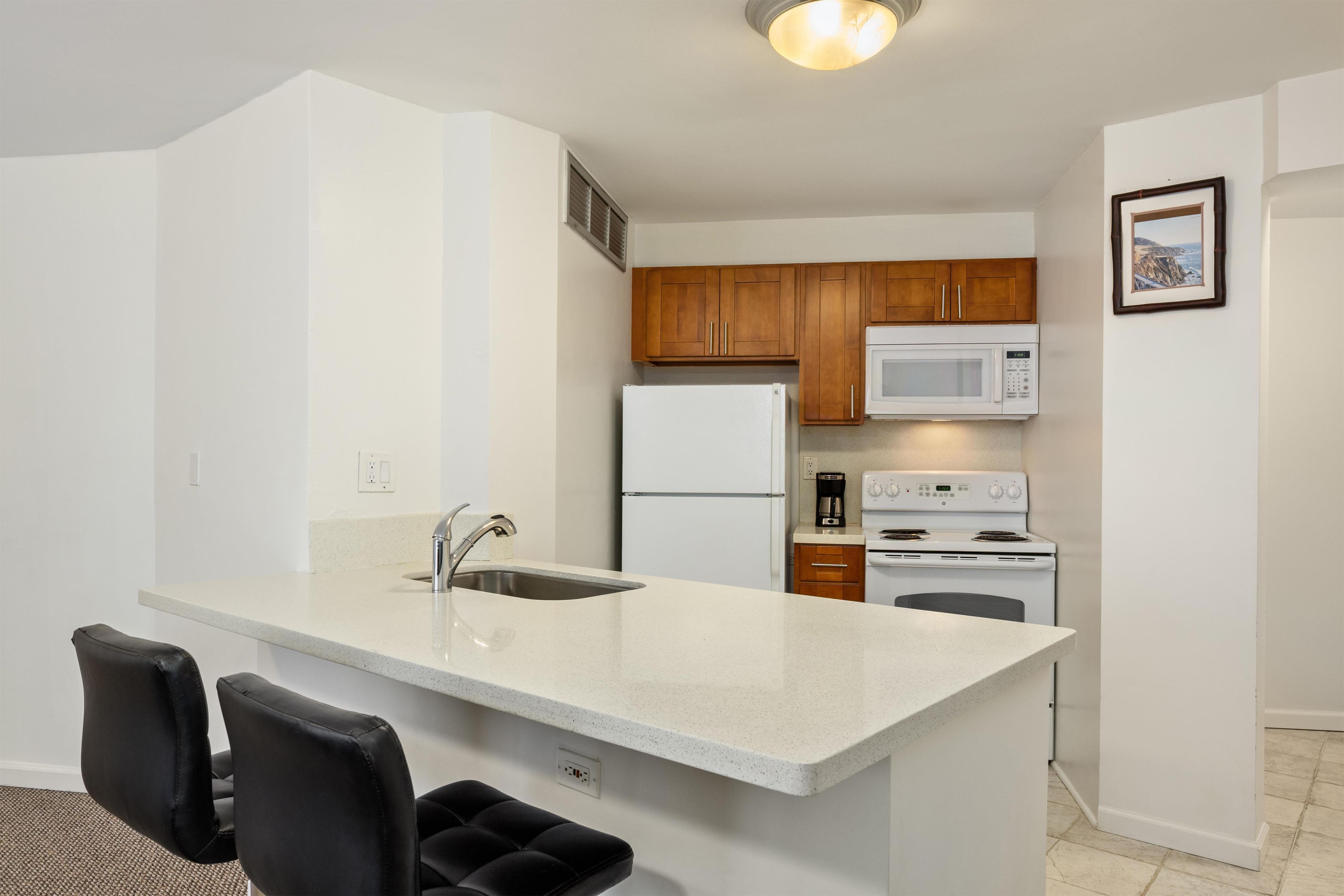 A modern kitchen with a central island, stainless steel appliances, and wooden cabinets.