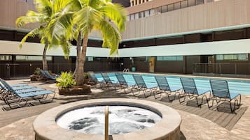 Un área de piscina con sillas de descanso, un jacuzzi y palmeras.