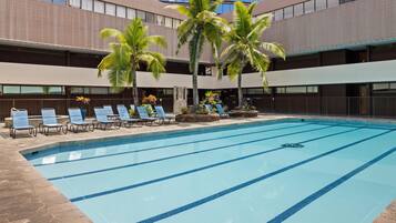 A swimming pool with blue lane dividers, surrounded by lounge chairs and palm trees.