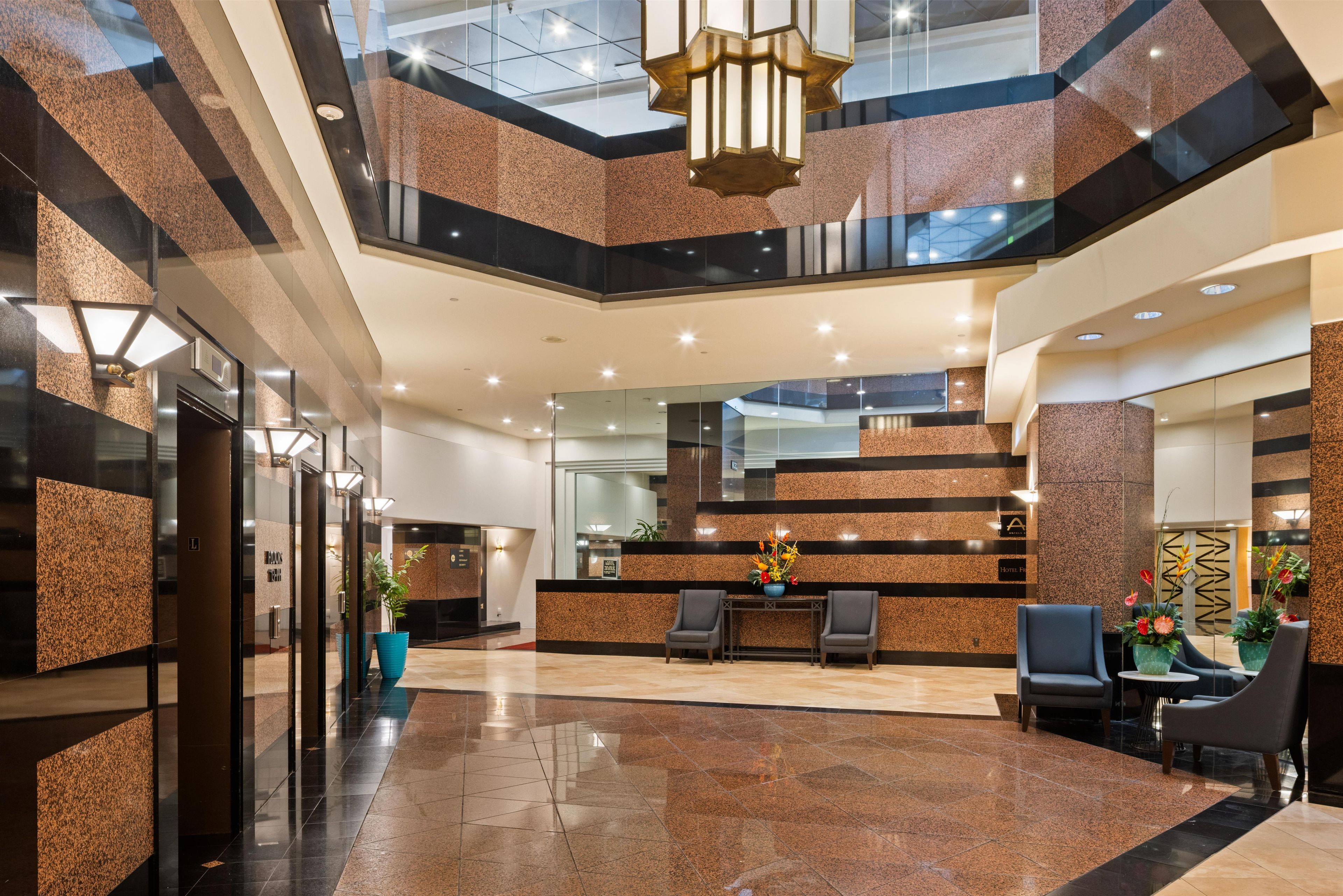Eine Hotelhalle mit Rezeption, einer Sitzecke und einer Treppe.