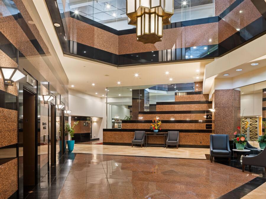 Un vestíbulo de hotel con mostrador de recepción, zona de estar y una escalera.