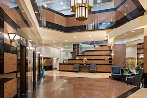 A hotel lobby with a reception desk, seating area, and a staircase.